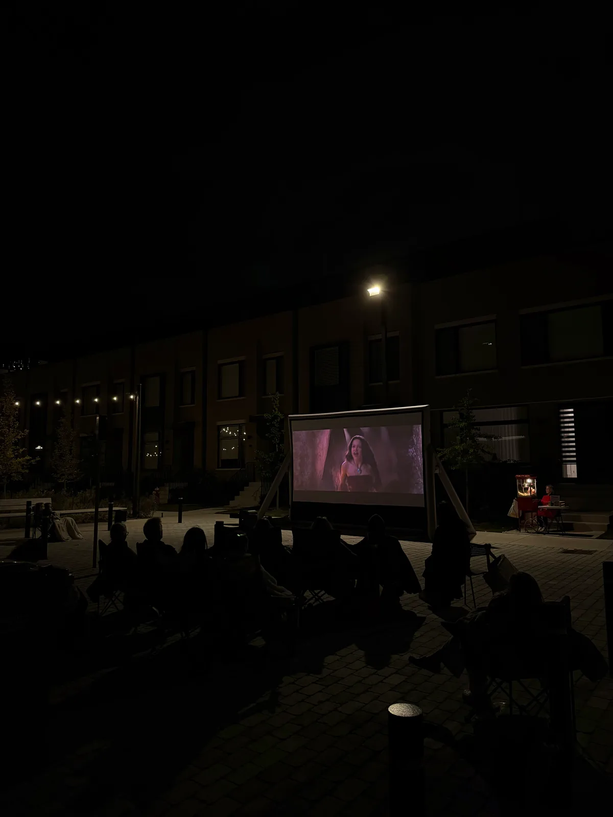 Guests seated in a courtyard for an outdoor movie at night