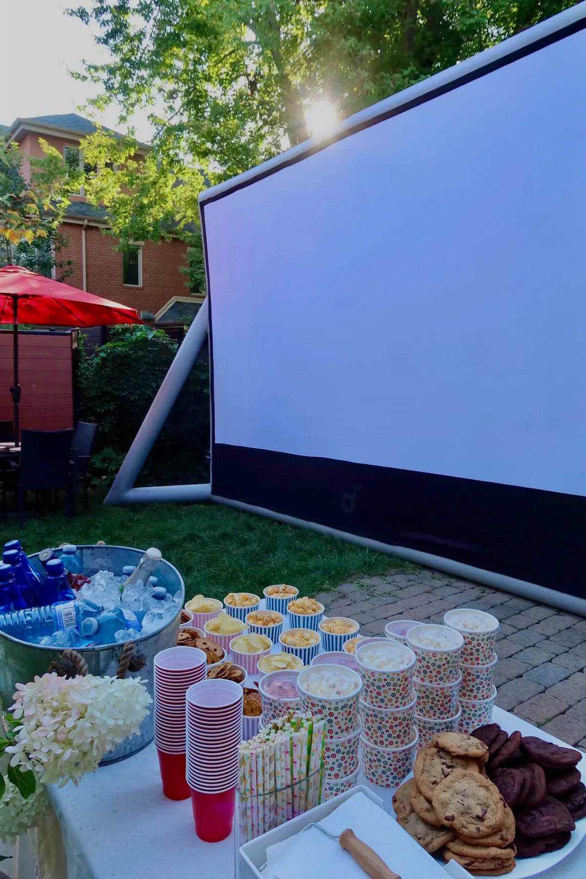 Backyard movie screen with a table of popcorn, drinks and snacks