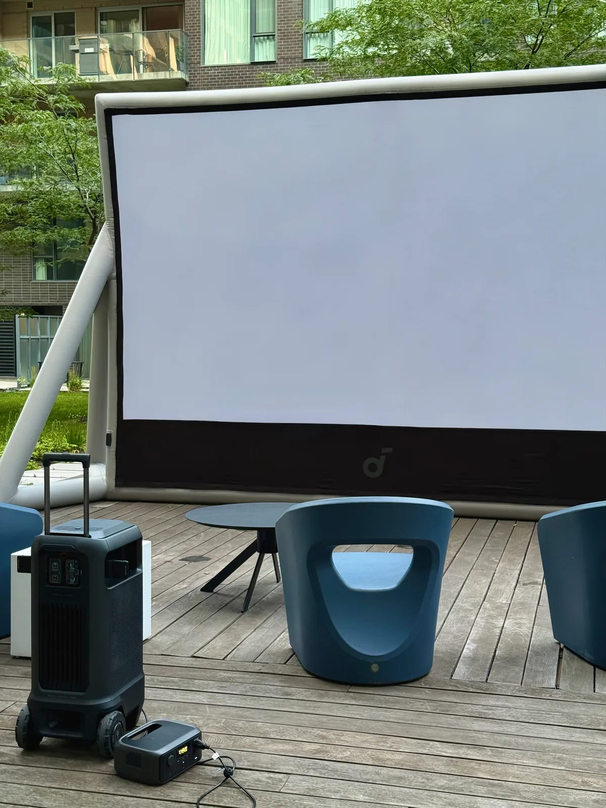 Outdoor screen and projector beside lounge seating on a terrace