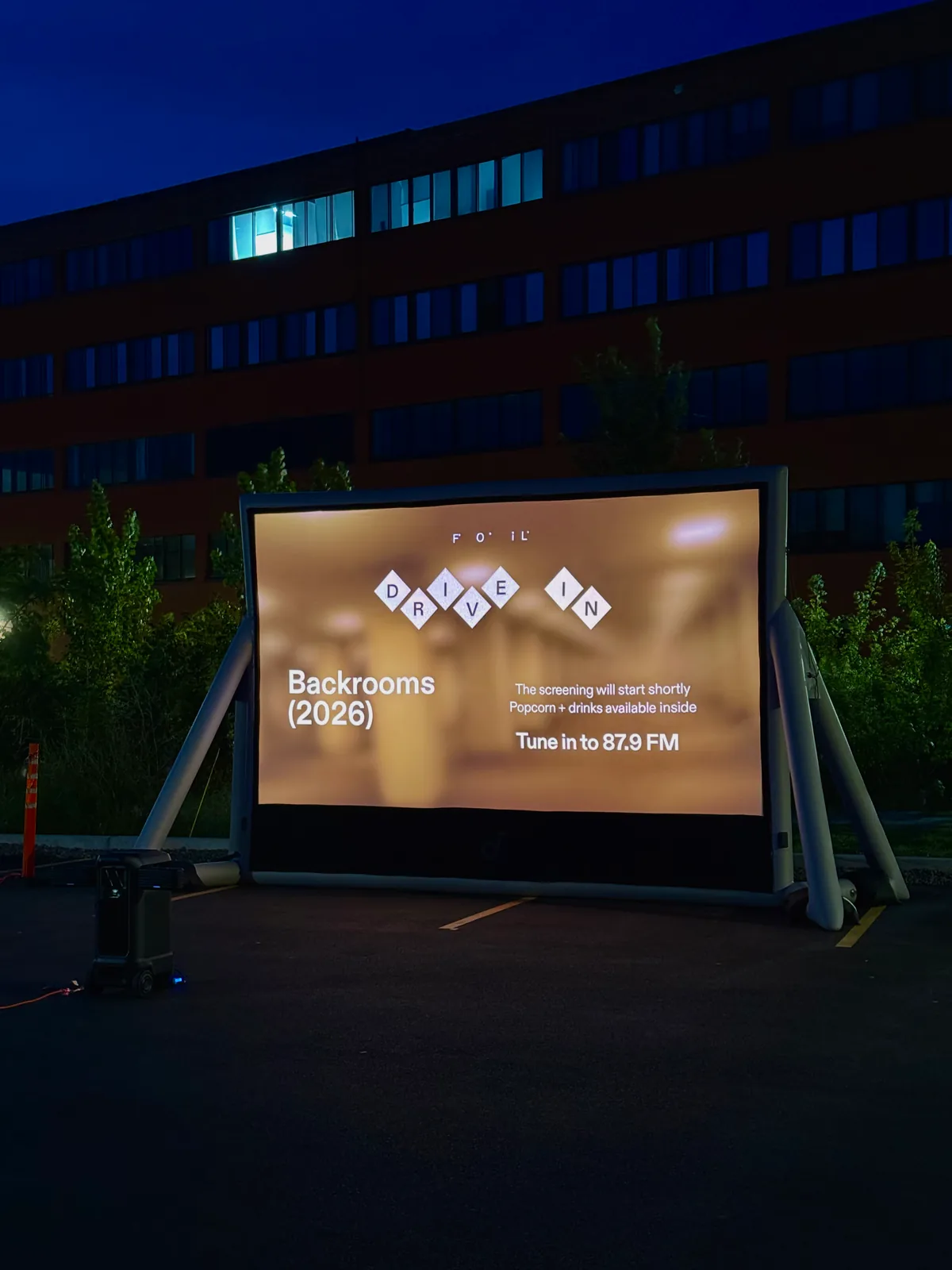 Drive-in movie screen in a parking lot at dusk